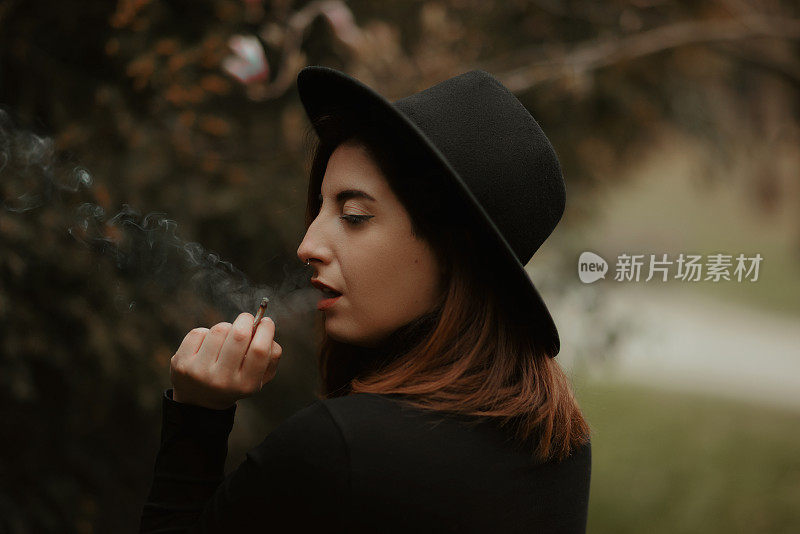 Young redhead woman portrait holding and smoking cigarette with eyes closed